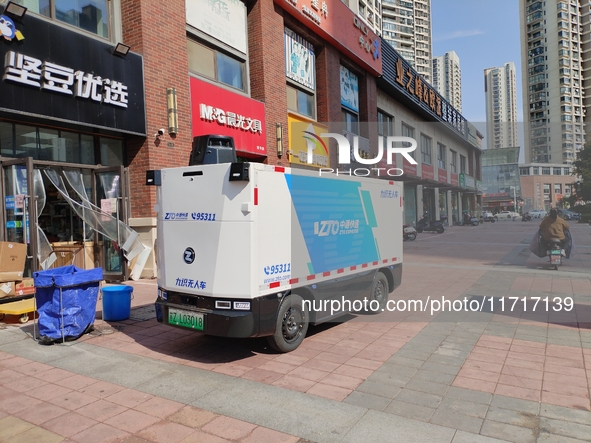 An unmanned delivery vehicle delivers packages for customers at a courier point in downtown Huai'an city, East China's Jiangsu province, on...