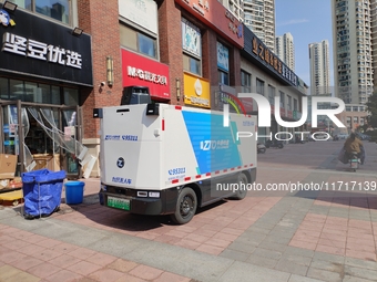 An unmanned delivery vehicle delivers packages for customers at a courier point in downtown Huai'an city, East China's Jiangsu province, on...