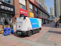 An unmanned delivery vehicle delivers packages for customers at a courier point in downtown Huai'an city, East China's Jiangsu province, on...