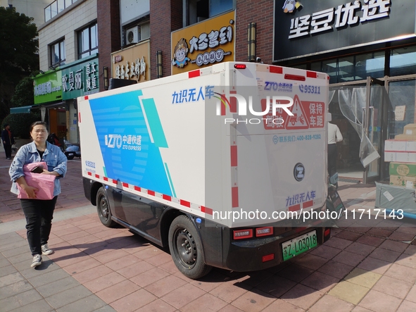 An unmanned delivery vehicle delivers packages for customers at a courier point in downtown Huai'an city, East China's Jiangsu province, on...