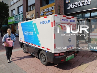 An unmanned delivery vehicle delivers packages for customers at a courier point in downtown Huai'an city, East China's Jiangsu province, on...