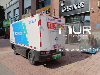 An unmanned delivery vehicle delivers packages for customers at a courier point in downtown Huai'an city, East China's Jiangsu province, on...