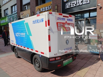 An unmanned delivery vehicle delivers packages for customers at a courier point in downtown Huai'an city, East China's Jiangsu province, on...