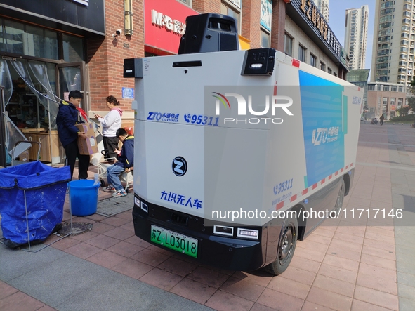 An unmanned delivery vehicle delivers packages for customers at a courier point in downtown Huai'an city, East China's Jiangsu province, on...