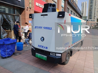 An unmanned delivery vehicle delivers packages for customers at a courier point in downtown Huai'an city, East China's Jiangsu province, on...