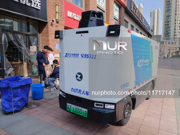 An unmanned delivery vehicle delivers packages for customers at a courier point in downtown Huai'an city, East China's Jiangsu province, on...