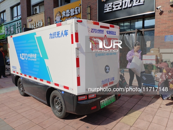 An unmanned delivery vehicle delivers packages for customers at a courier point in downtown Huai'an city, East China's Jiangsu province, on...