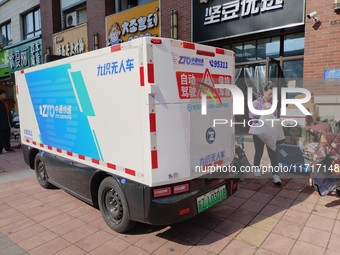 An unmanned delivery vehicle delivers packages for customers at a courier point in downtown Huai'an city, East China's Jiangsu province, on...