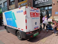 An unmanned delivery vehicle delivers packages for customers at a courier point in downtown Huai'an city, East China's Jiangsu province, on...