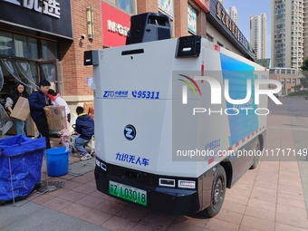 An unmanned delivery vehicle delivers packages for customers at a courier point in downtown Huai'an city, East China's Jiangsu province, on...