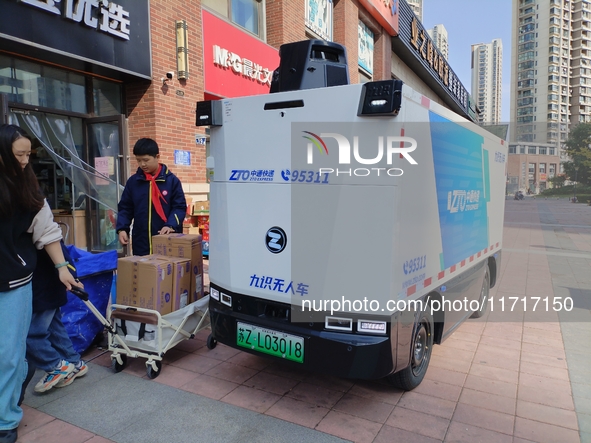 An unmanned delivery vehicle delivers packages for customers at a courier point in downtown Huai'an city, East China's Jiangsu province, on...