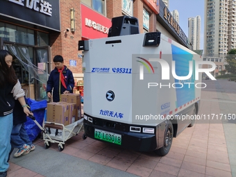 An unmanned delivery vehicle delivers packages for customers at a courier point in downtown Huai'an city, East China's Jiangsu province, on...