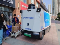 An unmanned delivery vehicle delivers packages for customers at a courier point in downtown Huai'an city, East China's Jiangsu province, on...