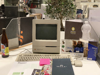 A close-up of an Apple Macintosh Classic II, an iconic vintage desktop computer, is set up on a modern workspace. This historical Apple mode...