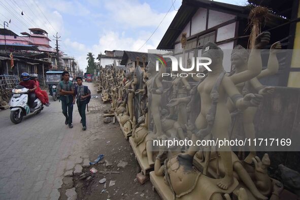 School students walk past semi-finished clay idols of the Hindu goddess Kali ahead of the Kali Puja and Diwali festival in Nagaon District,...