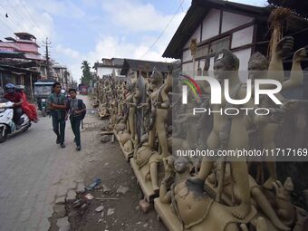 School students walk past semi-finished clay idols of the Hindu goddess Kali ahead of the Kali Puja and Diwali festival in Nagaon District,...