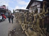 School students walk past semi-finished clay idols of the Hindu goddess Kali ahead of the Kali Puja and Diwali festival in Nagaon District,...