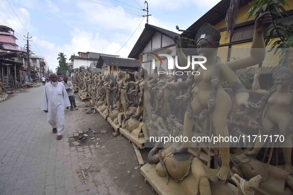 A man walks past semi-finished clay idols of the Hindu goddess Kali ahead of the Kali Puja and Diwali festival in Nagaon District, Assam, In...