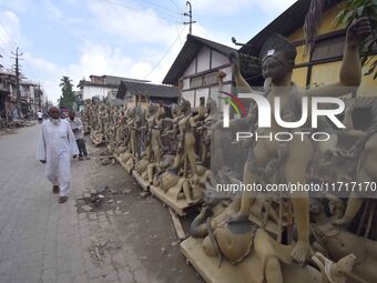 A man walks past semi-finished clay idols of the Hindu goddess Kali ahead of the Kali Puja and Diwali festival in Nagaon District, Assam, In...