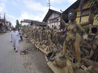 A man walks past semi-finished clay idols of the Hindu goddess Kali ahead of the Kali Puja and Diwali festival in Nagaon District, Assam, In...