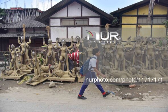 A school student walks past semi-finished clay idols of the Hindu goddess Kali ahead of the Kali Puja and Diwali festival in Nagaon District...