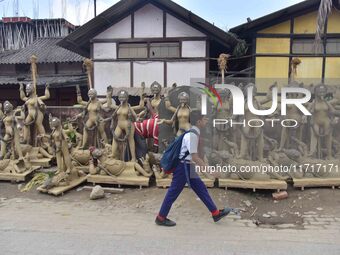 A school student walks past semi-finished clay idols of the Hindu goddess Kali ahead of the Kali Puja and Diwali festival in Nagaon District...