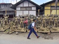 A school student walks past semi-finished clay idols of the Hindu goddess Kali ahead of the Kali Puja and Diwali festival in Nagaon District...