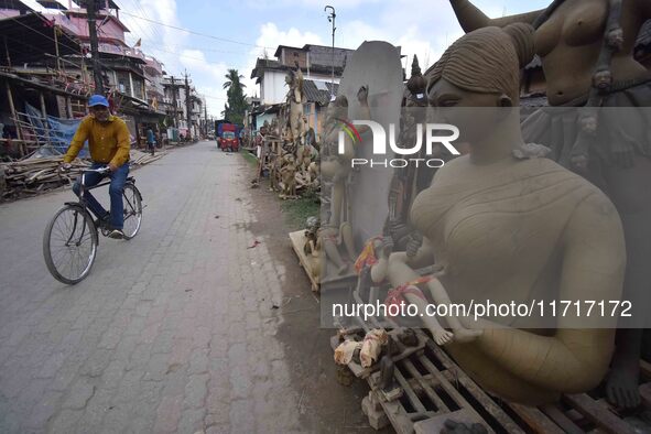 A man rides a bicycle past semi-finished clay idols of the Hindu goddess Kali ahead of the Kali Puja and Diwali festival in Nagaon District,...