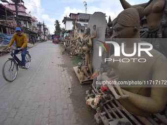 A man rides a bicycle past semi-finished clay idols of the Hindu goddess Kali ahead of the Kali Puja and Diwali festival in Nagaon District,...