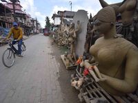 A man rides a bicycle past semi-finished clay idols of the Hindu goddess Kali ahead of the Kali Puja and Diwali festival in Nagaon District,...