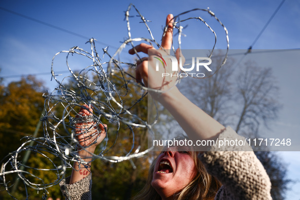 A woman holds barbed wire while attending a demonstration against the Polish government's plans to suspend the right to asylum for refugees...