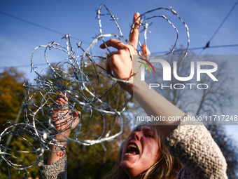 A woman holds barbed wire while attending a demonstration against the Polish government's plans to suspend the right to asylum for refugees...