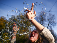 A woman holds barbed wire while attending a demonstration against the Polish government's plans to suspend the right to asylum for refugees...