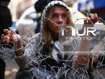 A woman holds barbed wire while attending a demonstration against the Polish government's plans to suspend the right to asylum for refugees...