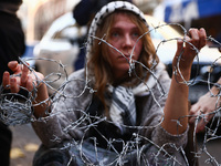 A woman holds barbed wire while attending a demonstration against the Polish government's plans to suspend the right to asylum for refugees...