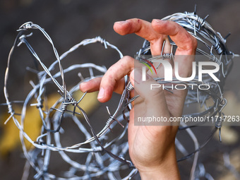 A person holds barbed wire while attending a demonstration against the Polish government's plans to suspend the right to asylum for refugees...