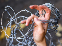 A person holds barbed wire while attending a demonstration against the Polish government's plans to suspend the right to asylum for refugees...