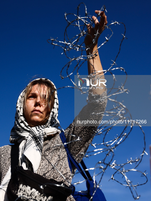 A woman holds barbed wire while attending a demonstration against the Polish government's plans to suspend the right to asylum for refugees...