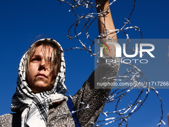 A woman holds barbed wire while attending a demonstration against the Polish government's plans to suspend the right to asylum for refugees...