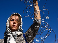 A woman holds barbed wire while attending a demonstration against the Polish government's plans to suspend the right to asylum for refugees...