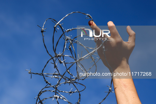 A person holds barbed wire while attending a demonstration against the Polish government's plans to suspend the right to asylum for refugees...