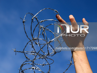 A person holds barbed wire while attending a demonstration against the Polish government's plans to suspend the right to asylum for refugees...