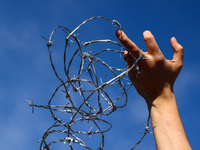 A person holds barbed wire while attending a demonstration against the Polish government's plans to suspend the right to asylum for refugees...