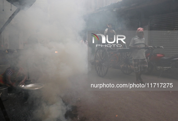 A hand-pulled rickshaw moves through thick smoke caused by the burning of coal ovens in an alley in Kolkata, India, on October 28, 2024. 