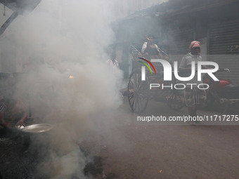 A hand-pulled rickshaw moves through thick smoke caused by the burning of coal ovens in an alley in Kolkata, India, on October 28, 2024. (