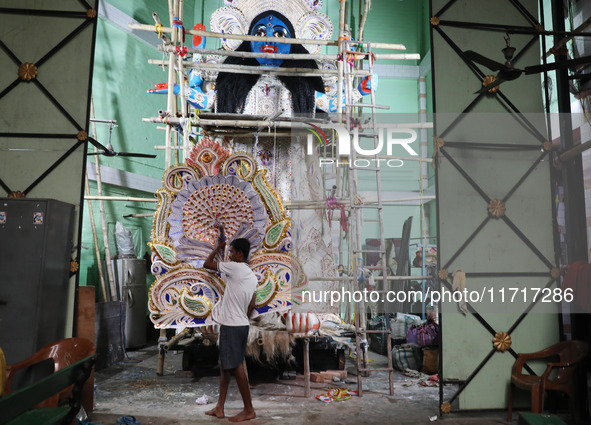 An artist carries a crown made with a thermocol sheet before decorating an idol of the Hindu goddess Kali inside a ''pandal'' (a temporary p...