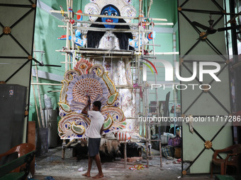 An artist carries a crown made with a thermocol sheet before decorating an idol of the Hindu goddess Kali inside a ''pandal'' (a temporary p...