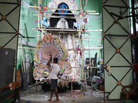 An artist carries a crown made with a thermocol sheet before decorating an idol of the Hindu goddess Kali inside a ''pandal'' (a temporary p...