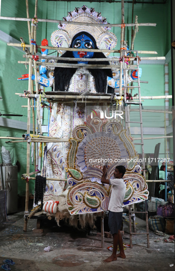 An artist carries a crown made with a thermocol sheet before decorating an idol of the Hindu goddess Kali inside a ''pandal'' (a temporary p...