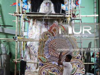 An artist carries a crown made with a thermocol sheet before decorating an idol of the Hindu goddess Kali inside a ''pandal'' (a temporary p...